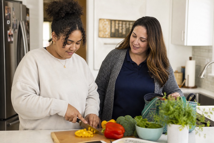 Young adult practicing daily living skills with caregiver support